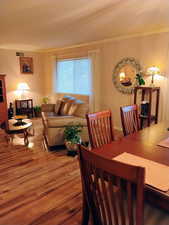 Dining space with wood finished floors and crown molding