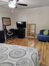 Office area featuring crown molding, light wood finished floors, and a ceiling fan