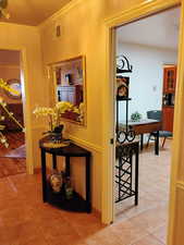 Corridor featuring crown molding and light tile patterned floors