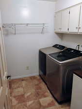 Washroom featuring washing machine and clothes dryer and cabinet space