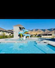 Community pool featuring a water slide, a mountain view, and a patio