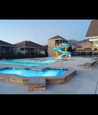 Community pool with a jacuzzi, a patio area, a water play area, and a mountain view