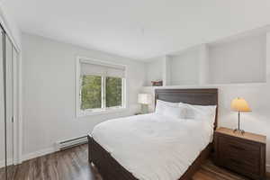Bedroom featuring baseboard heating, wood finished floors, and a closet