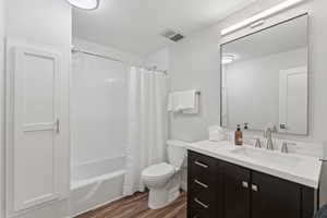 Full bathroom with vanity, wood finished floors, and shower / bath combo with shower curtain