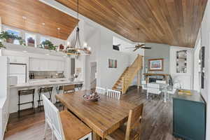 Dining space featuring wooden ceiling, stairs, ceiling fan, dark wood-style flooring, and a chandelier