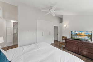 Bedroom featuring wood finished floors, lofted ceiling, ensuite bathroom, and a ceiling fan