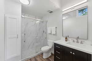 Bathroom with vanity, wood finished floors, and a marble finish shower