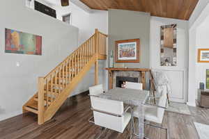 Dining area featuring stairway, wood finished floors, wood ceiling, vaulted ceiling, and a lit fireplace