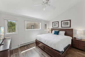 Bedroom with baseboard heating, vaulted ceiling, wood finished floors, and ceiling fan