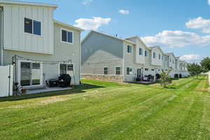 Rear view of property with board and batten siding, a patio area, a residential view, and a yard