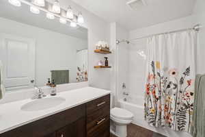 Bathroom with shower / bath combo with shower curtain, vanity, and dark wood-style flooring