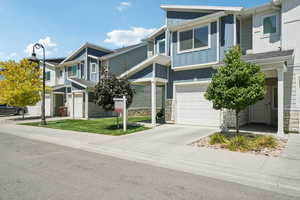 View of front of property featuring board and batten siding, an attached garage, stone siding, and concrete driveway