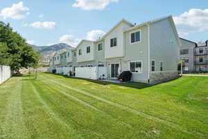 Rear view of property with a residential view, a mountain view, board and batten siding, a patio, and stone siding