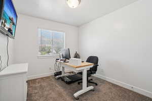 Home office with dark colored carpet and baseboards