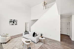Living area with a high ceiling, light wood finished floors, and a chandelier