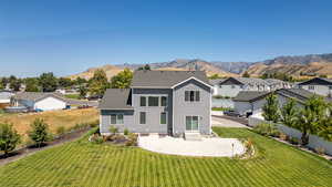 Rear view of property with a patio, a residential view, a lawn, a mountain view, and entry steps
