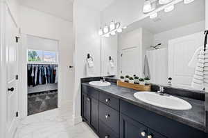 Full bathroom with light marble finish floors, a walk in closet, and a shower with shower curtain