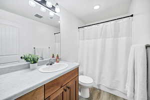 Bathroom with vanity, light wood-style floors, shower / tub combo with curtain, and recessed lighting