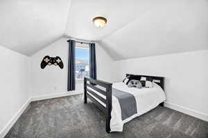 Carpeted bedroom with vaulted ceiling and baseboards