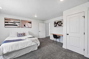 Carpeted bedroom with an office area and recessed lighting