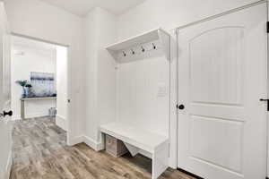 Mudroom with light wood-style floors and baseboards
