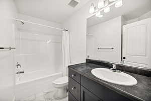 Bathroom with shower / bath combo with shower curtain, vanity, and light marble finish flooring