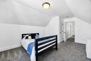Bedroom featuring dark carpet and vaulted ceiling