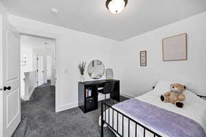 Bedroom featuring dark carpet and baseboards