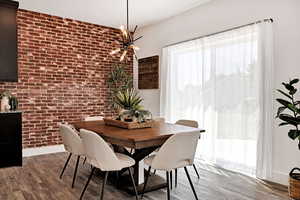 Dining room featuring brick wall, wood finished floors, and a chandelier