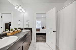 Bathroom with light marble finish flooring, ensuite bathroom, and a shower with curtain