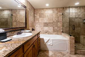 Bathroom featuring tile walls, vanity, a bath, a stall shower, and a textured ceiling