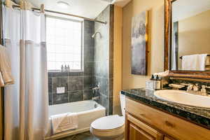 Full bath featuring shower / tub combo, vanity, a textured ceiling, and a textured wall