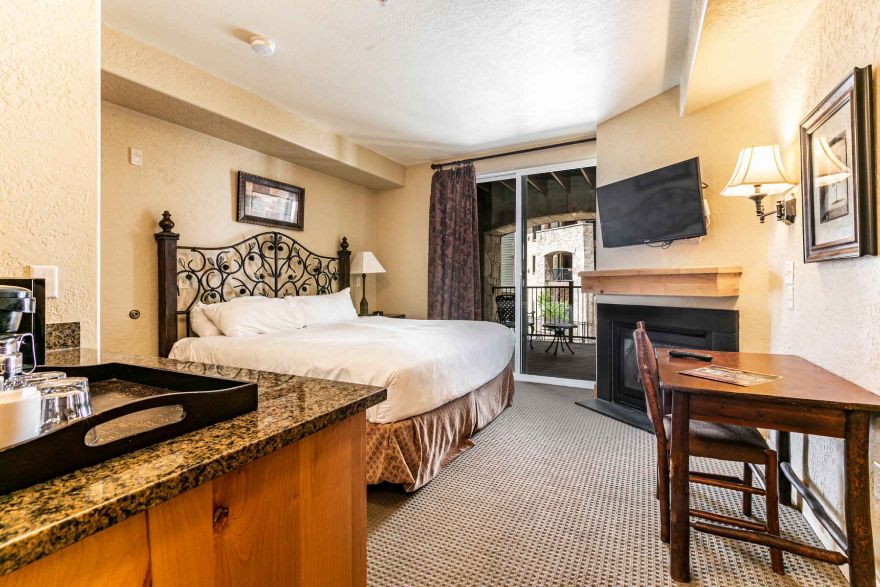 Bedroom featuring a textured wall, access to exterior, carpet flooring, a glass covered fireplace, and a textured ceiling