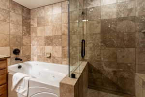 Full bath featuring a shower stall, a jetted tub, tile walls, and vanity