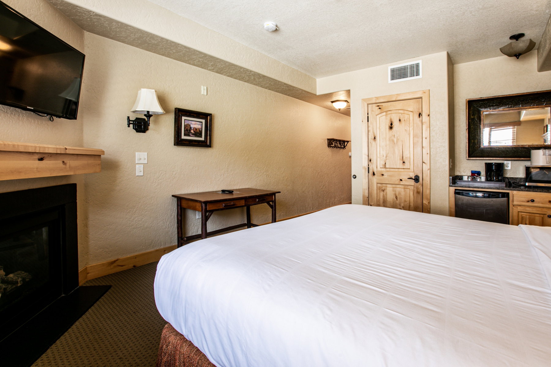 Bedroom featuring a textured wall, a fireplace, a textured ceiling, and dark carpet