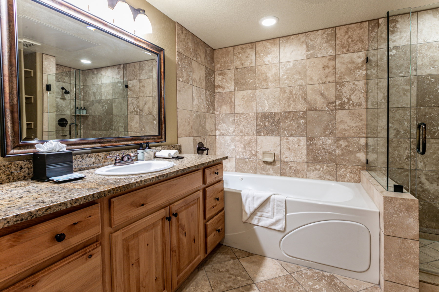 Bathroom featuring vanity, a bath, a shower stall, tile walls, and light tile patterned floors