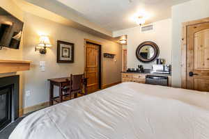 Bedroom featuring a textured wall, a glass covered fireplace, and a textured ceiling