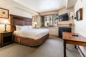 Bedroom featuring a textured wall, carpet, and a glass covered fireplace