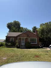 View of front of property featuring brick siding, a front lawn, and a chimney