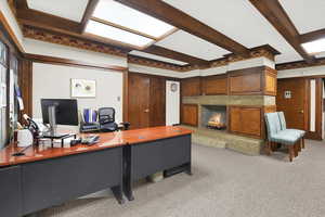 Office area with beam ceiling, light colored carpet, and a high end fireplace
