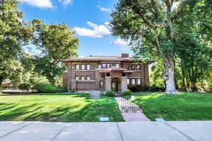 View of front of house with a front lawn, brick siding, and a chimney