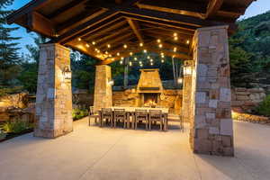 View of patio featuring outdoor dining area and an outdoor stone fireplace
