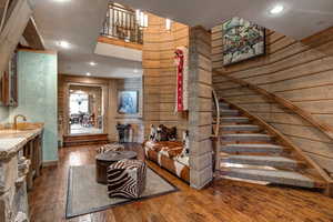 Living area with recessed lighting, dark wood-type flooring, wooden walls, and stairway