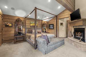 Bedroom featuring wood walls, carpet, recessed lighting, a fireplace, and high vaulted ceiling