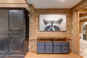 Home theater featuring wooden walls and light wood-style floors