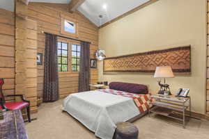 Bedroom with beamed ceiling, carpet flooring, wood walls, and high vaulted ceiling
