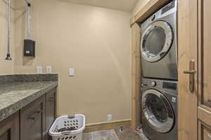 Laundry area featuring stacked washer / drying machine and baseboards
