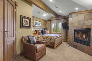 Carpeted bedroom featuring a tiled fireplace, recessed lighting, and wood walls