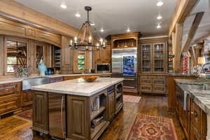 Kitchen with open shelves, light stone counters, built in appliances, dark wood finished floors, and recessed lighting