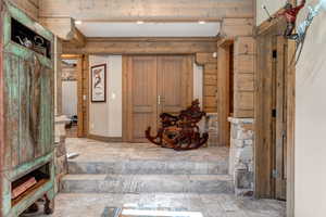 Foyer entrance with stone tile flooring and beamed ceiling